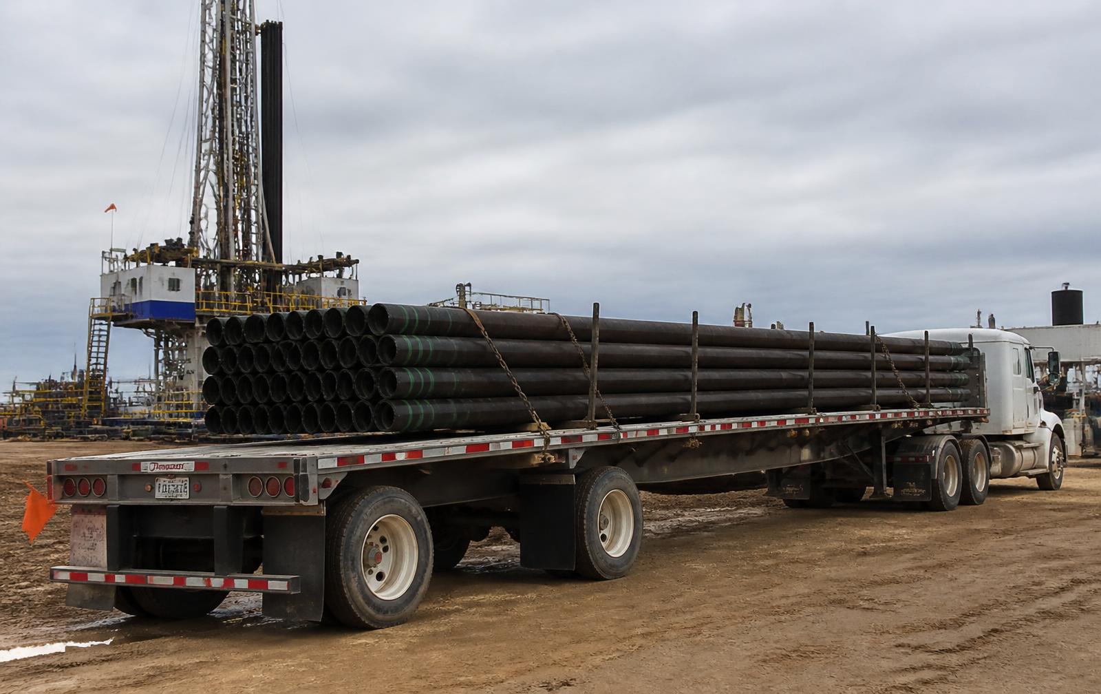 Flatbed truck loaded with 2-7/8 inch drill pipe at a drilling location